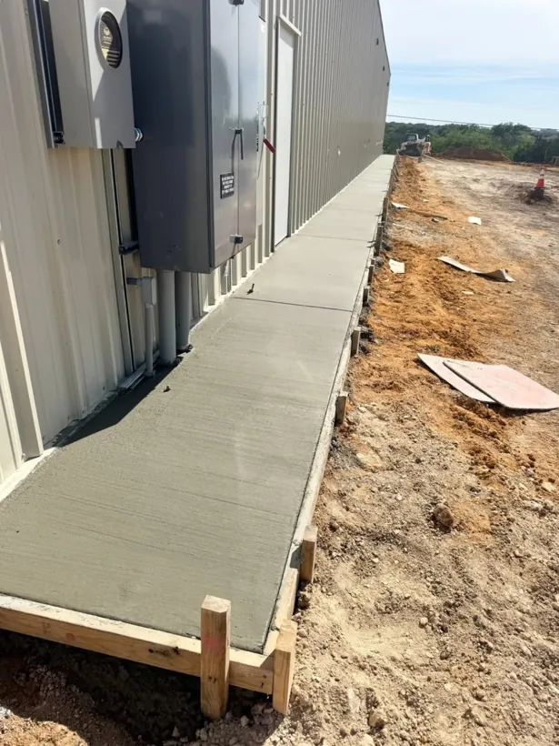 Finished concrete walkway running the length of a metal building