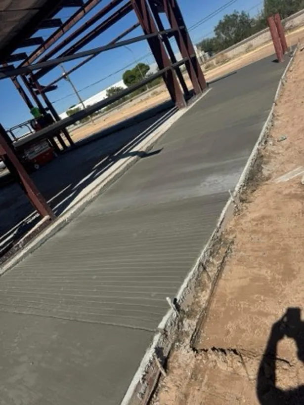 Finished concrete walkway under a steel canopy frame