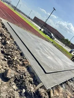 Finished concrete pad beside a school running track