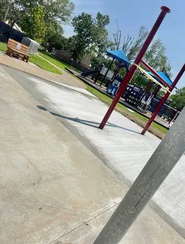 Finished concrete plaza at a playground with shade posts set