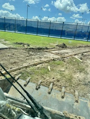 Walkway forms and rebar run along the tennis court fence